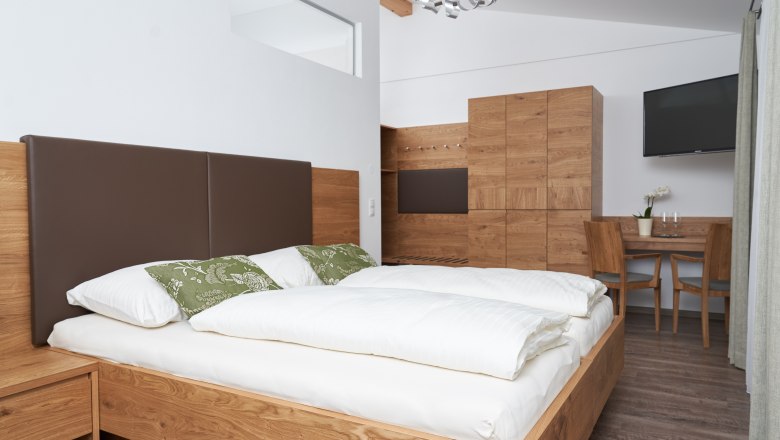 Rooms in the Weinhof, © Weinhof Maier Modern bedroom with wooden furniture, double bed, table and chairs.