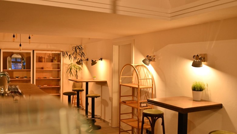 BREADLEY BISTRO, © Marek Safranek Innenansicht eines gemütlichen Cafés mit Holzmöbeln und warmem Licht.