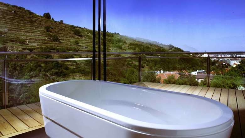 Vineyard suite - panoramic bathroom, © Steigenberger Hotel and Spa Panoramic view from a bathroom with bathtub and view of vineyards.