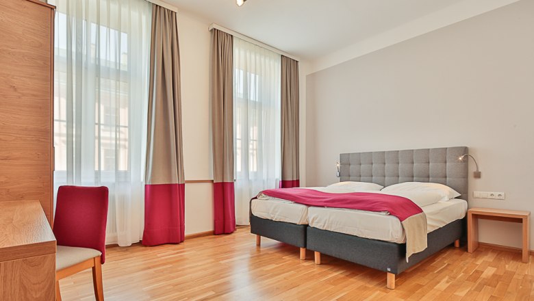 Hotel Unter den Linden Room 104, © Hotel Unter den Linden Bright hotel room with double bed, desk and chair.