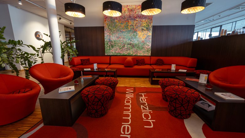 arte Hotel Krems, © Niederösterreich Werbung / Maximilian Pawlikowsky Modern hotel lobby with red furniture and artwork on the wall.