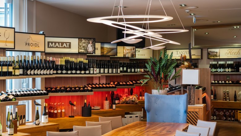 Top wineries from the Krems Valley ("Kremstal" in German) and the Wachau., © Wellen.Spiel Interior view of a wine store with shelves full of wine bottles and modern lighting.
