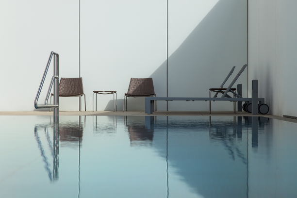 Outdoor pool, © Friedl&Partner, Klinglhuber GmbH Modern outdoor pool with two chairs and a lounger against a white wall.