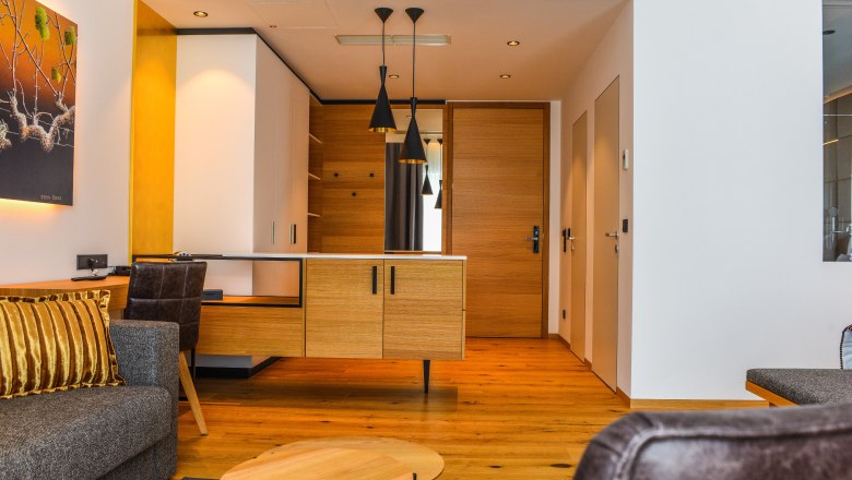 Suite Hotel Klinglhuber, © Klinglhuber Interior view of a modern hotel suite with wooden floor, gray sofa and wooden desk.