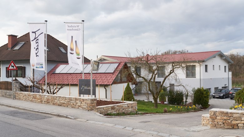 Aussenansicht, © Weinhof Maier Außenansicht eines Gebäudes mit roten Dächern und zwei Fahnen davor.