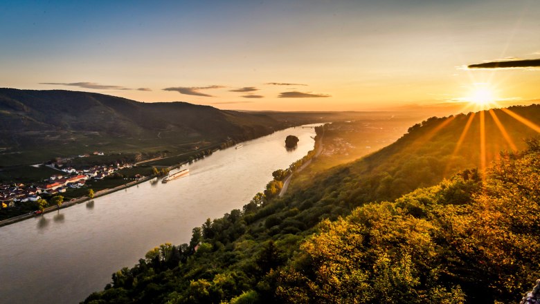 Ausblick von der Ferdinand-Warte, © Robert Herbst Sonnenuntergang über einem Fluss mit Hügeln und Dörfern im Hintergrund.