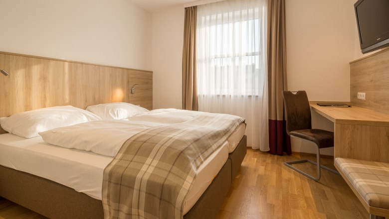 Hotel Unter den Linden Room 215, © Hotel Unter den Linden Hotel room with double bed, desk and window with curtains.