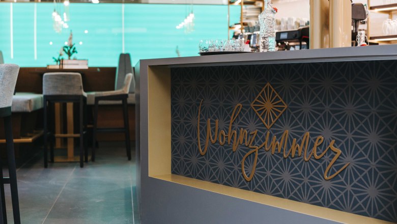 Café living room logo, © FMS Steinertor Gastronomie BetriebsgmbH Interior view of a café with the lettering 'Wohnzimmer' on a counter.