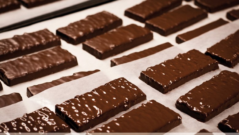 Confectionery Hagmann, © Konditorei Hagmann Chocolate-covered cookies on baking paper in a patisserie.