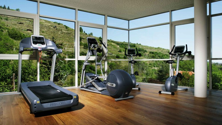 Fitness room, © Steigenberger Hotel and SPa Fitness room with treadmill, cross trainer and exercise bike in front of large windows with a view of green hills.