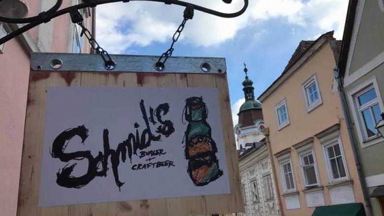 Willkommen im Schmid's, © Schmid's Schild von Schmid's Burger und Craftbeer an einer Hauswand in einer Altstadtstraße.