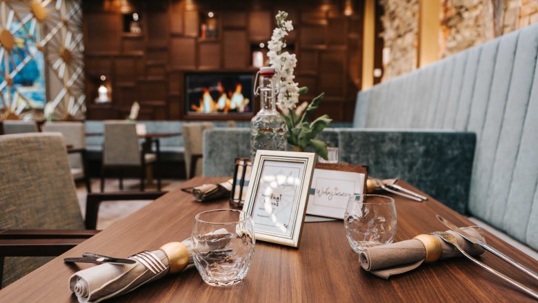 Café living room detail, © FMS Steinertor Gastronomie BetriebsgmbH A stylishly laid table in a café with wooden decor and a fireplace in the background.