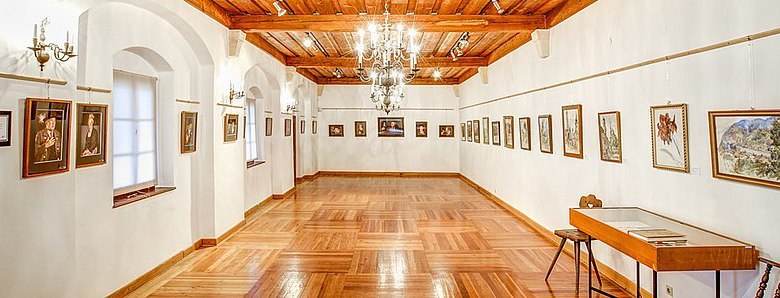 Buresch_Room, © Benno Bertl An elegant showroom with a wooden floor, white walls and paintings on the walls.