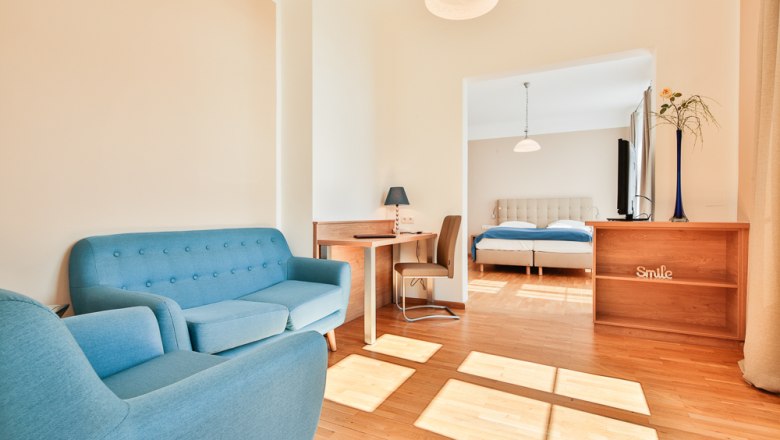 Hotel Unter den Linden Room 208, © Hotel Unter den Linden Bright hotel room with blue furniture and double bed.