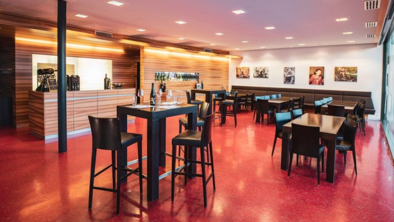 Verkostungsraum, © Michael Parak Moderner Verkostungsraum mit Holztresen, roten Bodenfliesen und schwarzen Tischen und Stühlen.