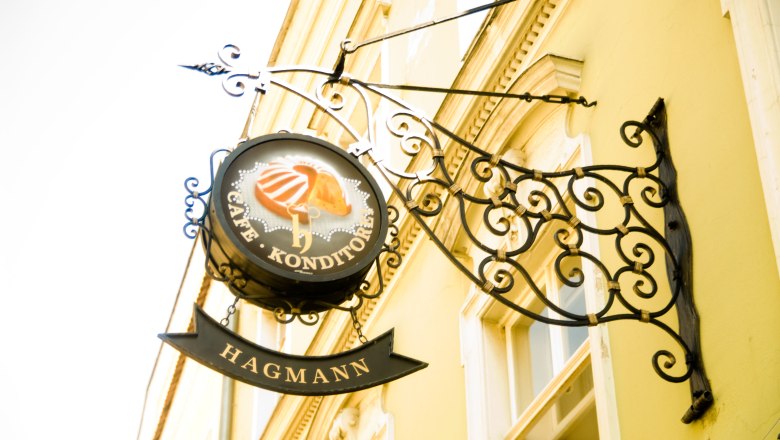 Confectionery Hagmann, © Konditorei Hagmann Metal sign 'Café Konditorei Hagmann' on a yellow house wall.