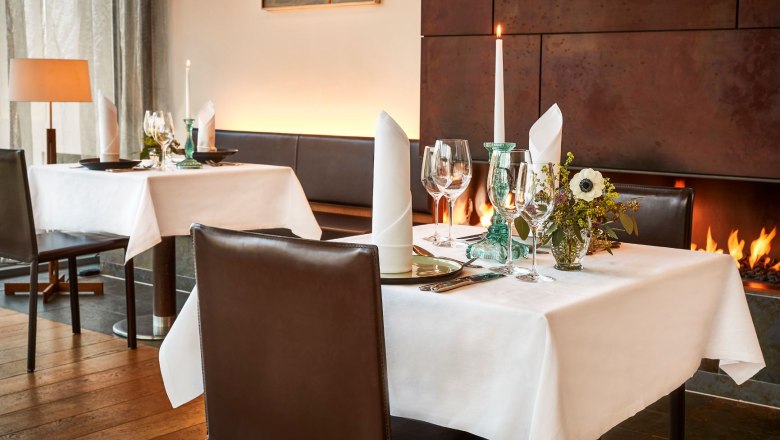 Cuve Club Restaurant, © Steigenberger Hotel and Spa, Gregor Titze Elegant restaurant with laid table, candles and fireplace.