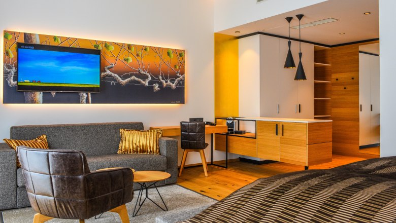 Suite example at Klinglhuber, © Franz Klinglhuber GmbH Modern hotel suite with sofa, armchair, TV and kitchenette.