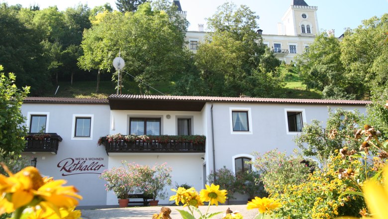 Exterior view of the Rethaller family, © rethaller Exterior view of a house with flowers and a building in the background.