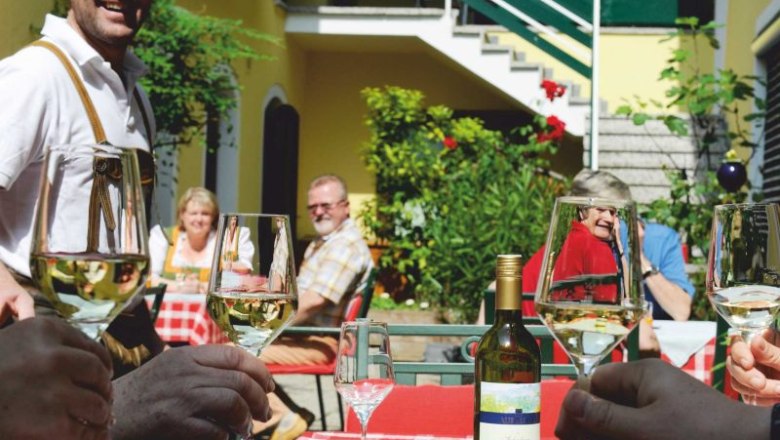 Gesellige Runde im Innenhof, © Steve Haider Menschen stoßen mit Weingläsern im sonnigen Innenhof an.