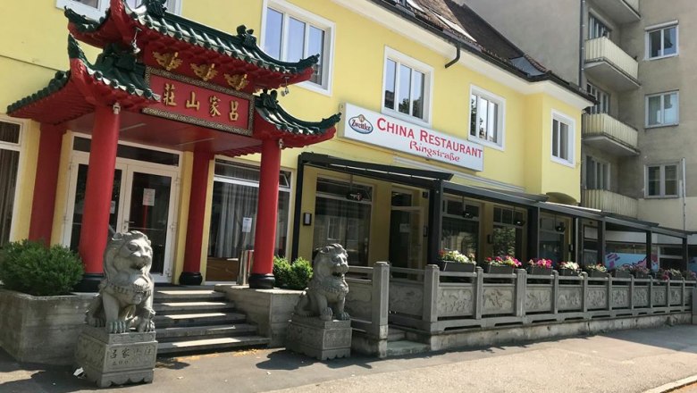 chinarestaurant-shanghai, © Chinarestaurant Shanghai Exterior view of a Chinese restaurant with traditional gate and lion statues.