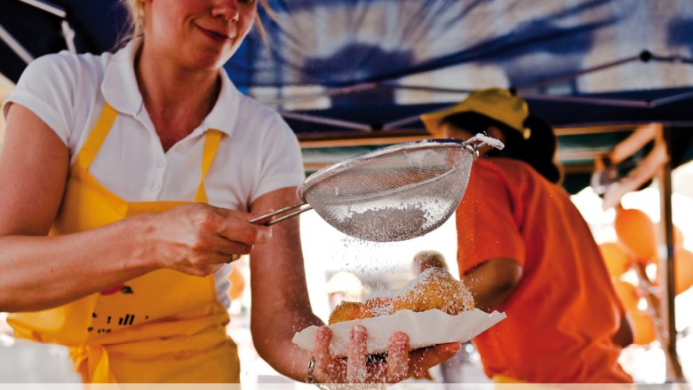 Confectionery Hagmann, © Konditorei Hagmann A woman dusts pastries with powdered sugar through a sieve.