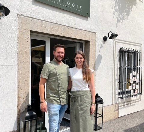 Bernhard & Elisabeth, © Elisabeth Pammer Ein Mann und eine Frau stehen vor einem Café namens Trilogie.