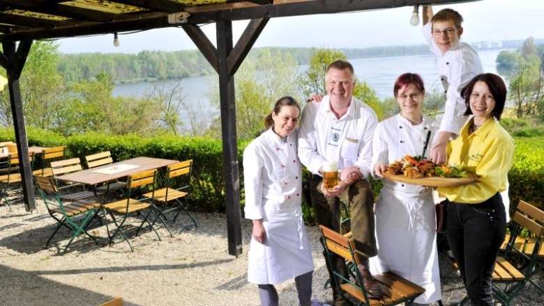 Das Team vom Lumpazi Bräu, © Lumpazi Bräu Ein Team von fünf Personen in einem Biergarten mit Blick auf einen Fluss.