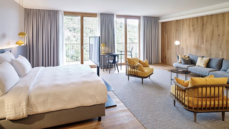 Steigenberger Krems, Goldberg, © Steigenberger Hotel and Spa, Gregor Titze Modern hotel room with large bed, seating area and desk in front of large windows.