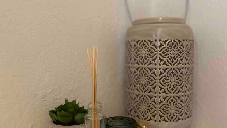 Dekobeispiel, © Familie Stagard Dekorative Anordnung mit Duftstäbchen, Kerze, Sukkulente und Laterne auf einem weißen Regal.