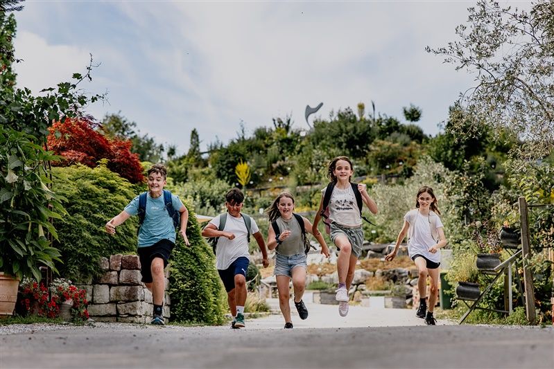 Fünf Kinder rennen fröhlich durch einen Gartenweg in den Kittenberger Erlebnisgärten.