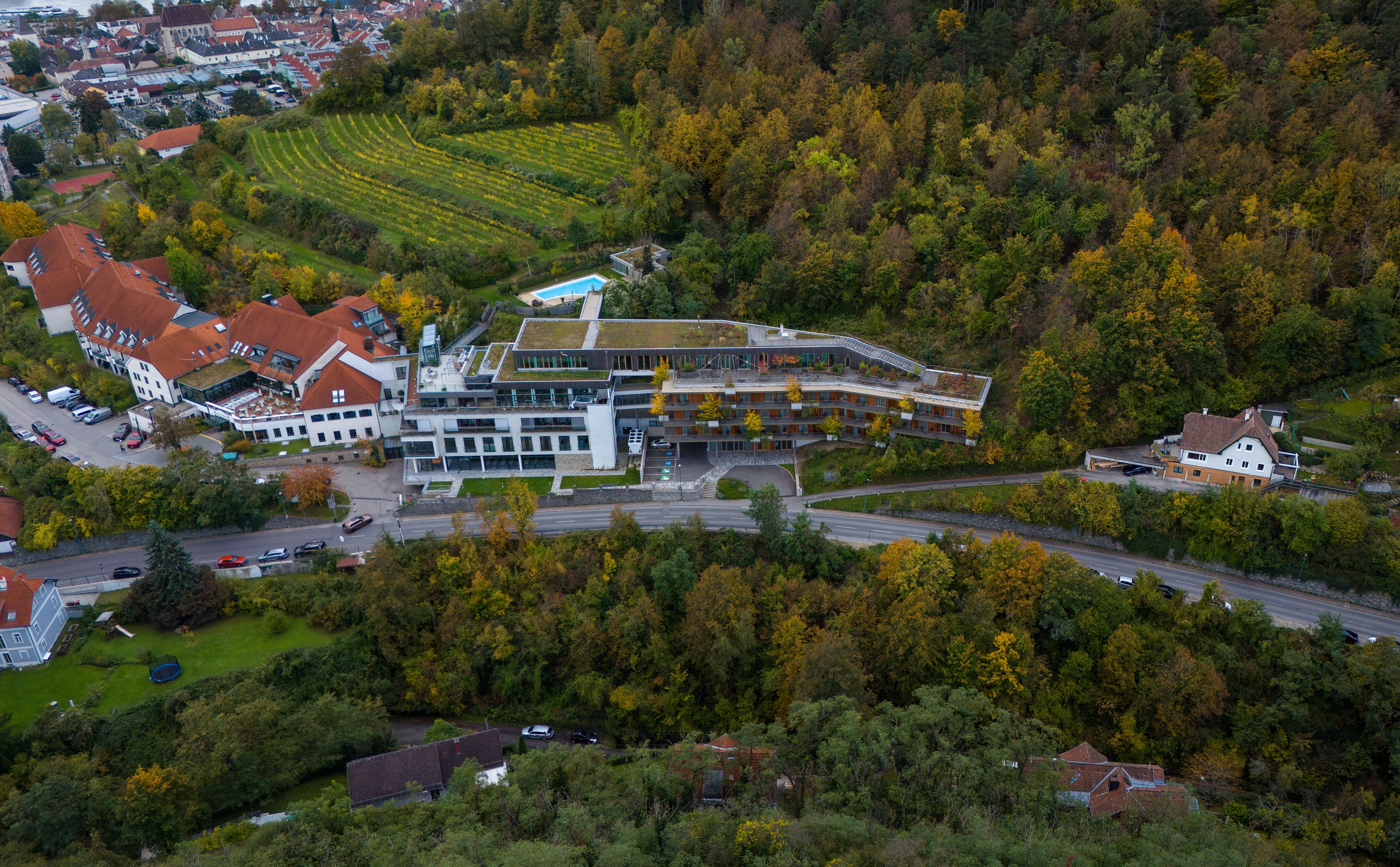 Luftaufnahme des Steigenberger Hotel & Spa in Krems, umgeben von Wald und Weinbergen.