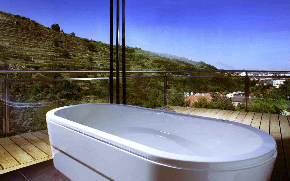 Panoramablick aus einem Badezimmer mit Badewanne und Blick auf Weinberge.