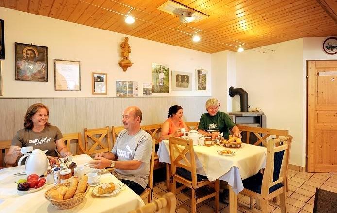 Menschen fr&uuml;hst&uuml;cken in einem gem&uuml;tlichen Raum mit Holzm&ouml;beln und Dekorationen an der Wand.