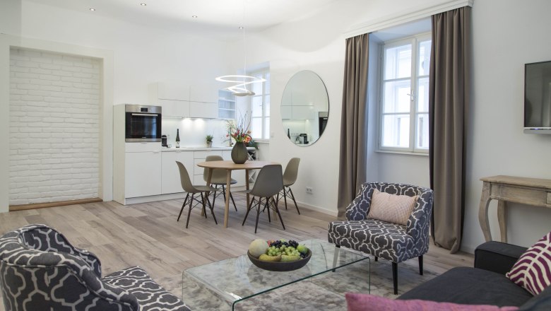 Modern living room with kitchen, dining table and stylish furniture.