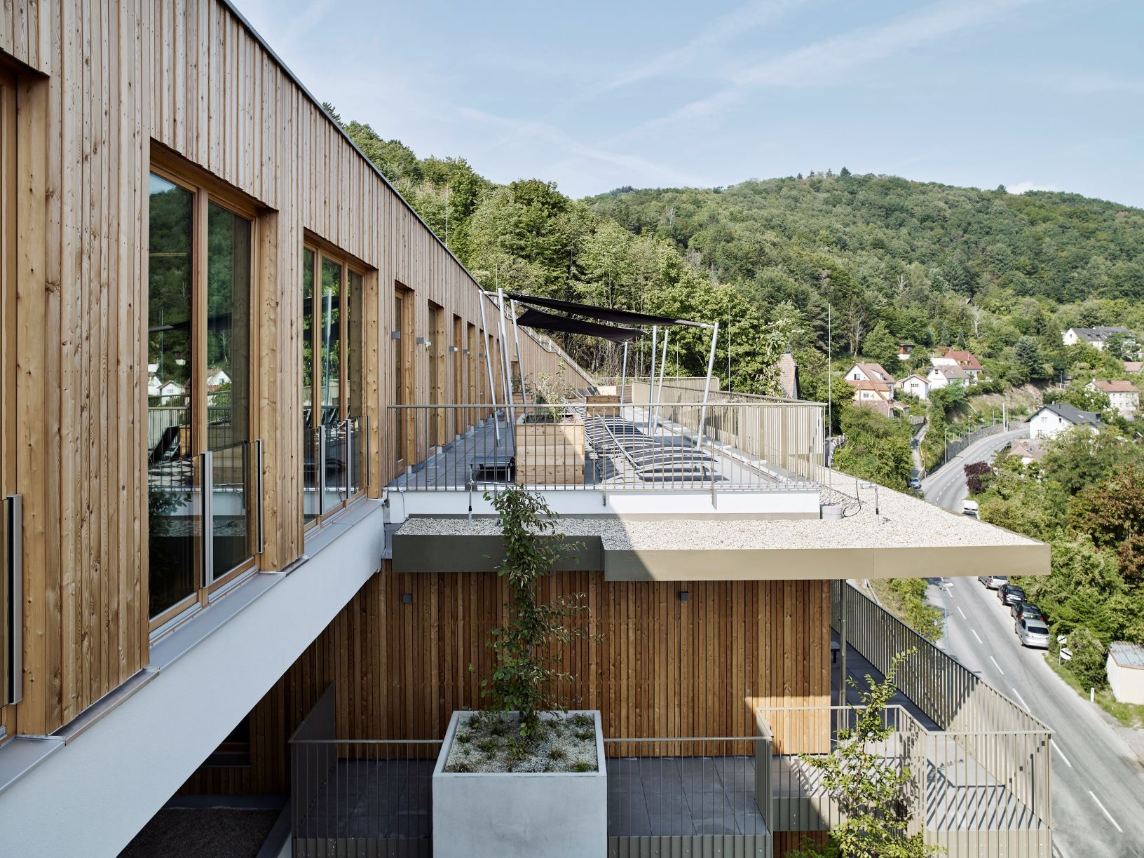 Moderne Spa-Terrasse mit Holzverkleidung und Blick auf bewaldete Hügel.