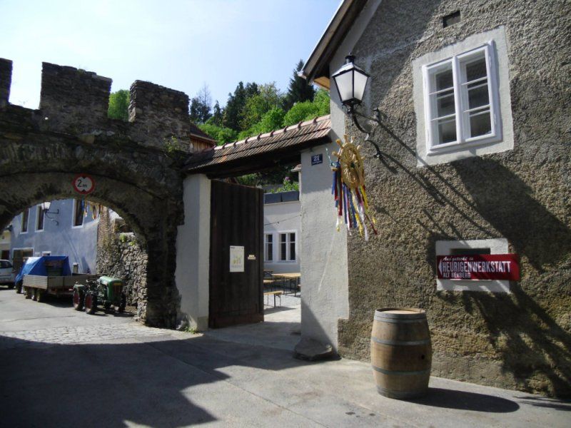 Eingang zu einem traditionellen Heurigen mit Torbogen und Schild.