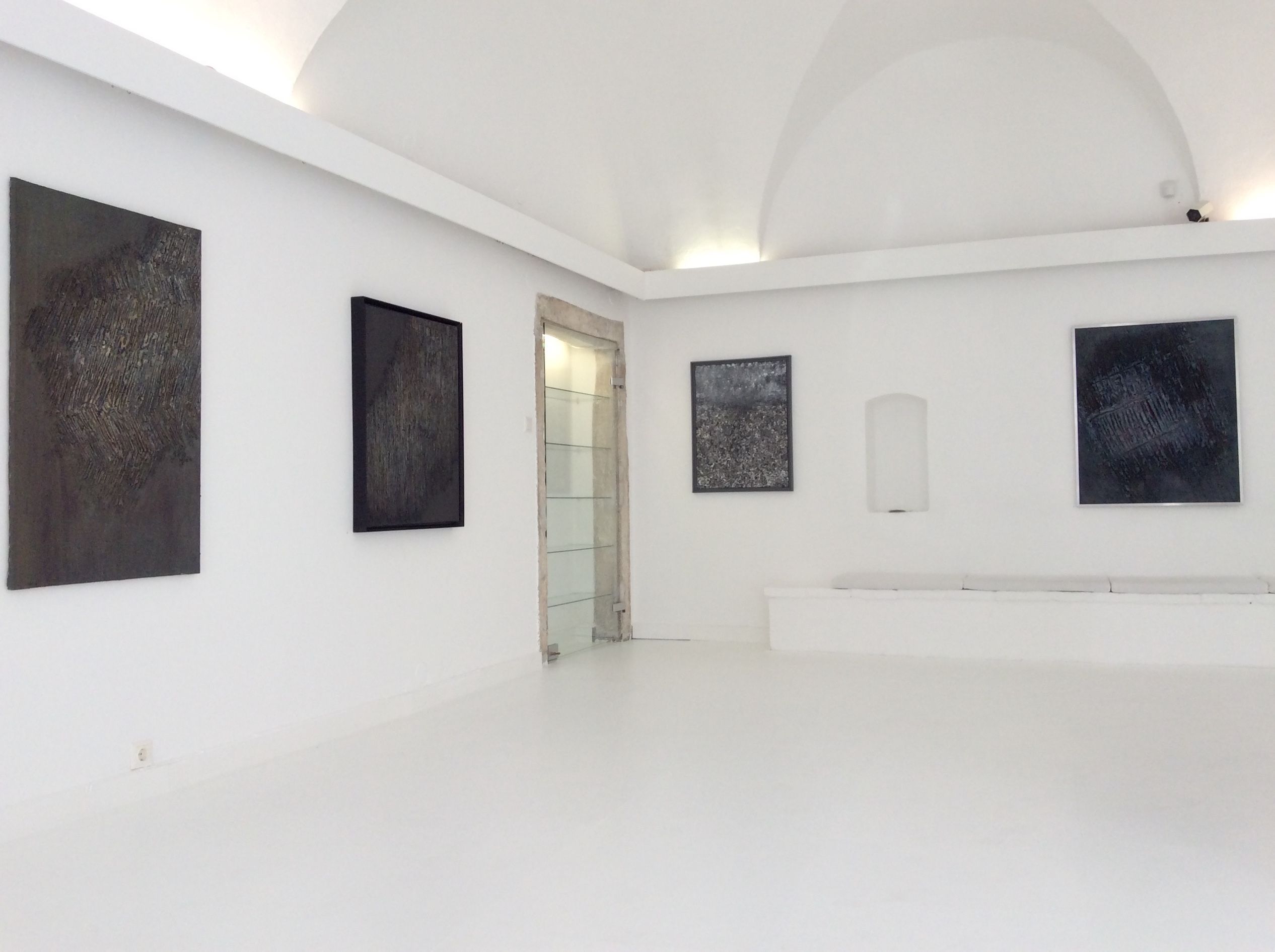Innenansicht einer Galerie mit abstrakten Gemälden an weißen Wänden.