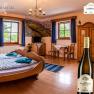 Cozy room with wooden furniture, a barrel bed and a bottle of wine in the foreground.