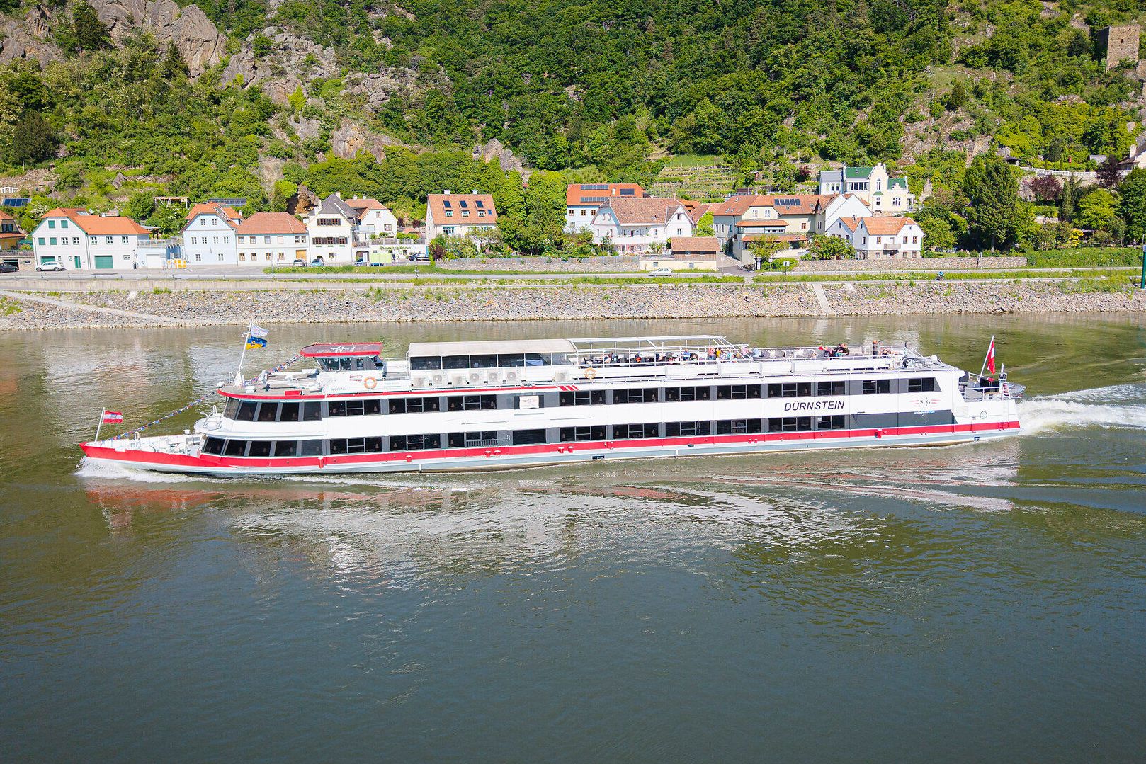 Ein Schiff fährt auf der Donau und im Hintergrund ist Dürnstein zu sehen.