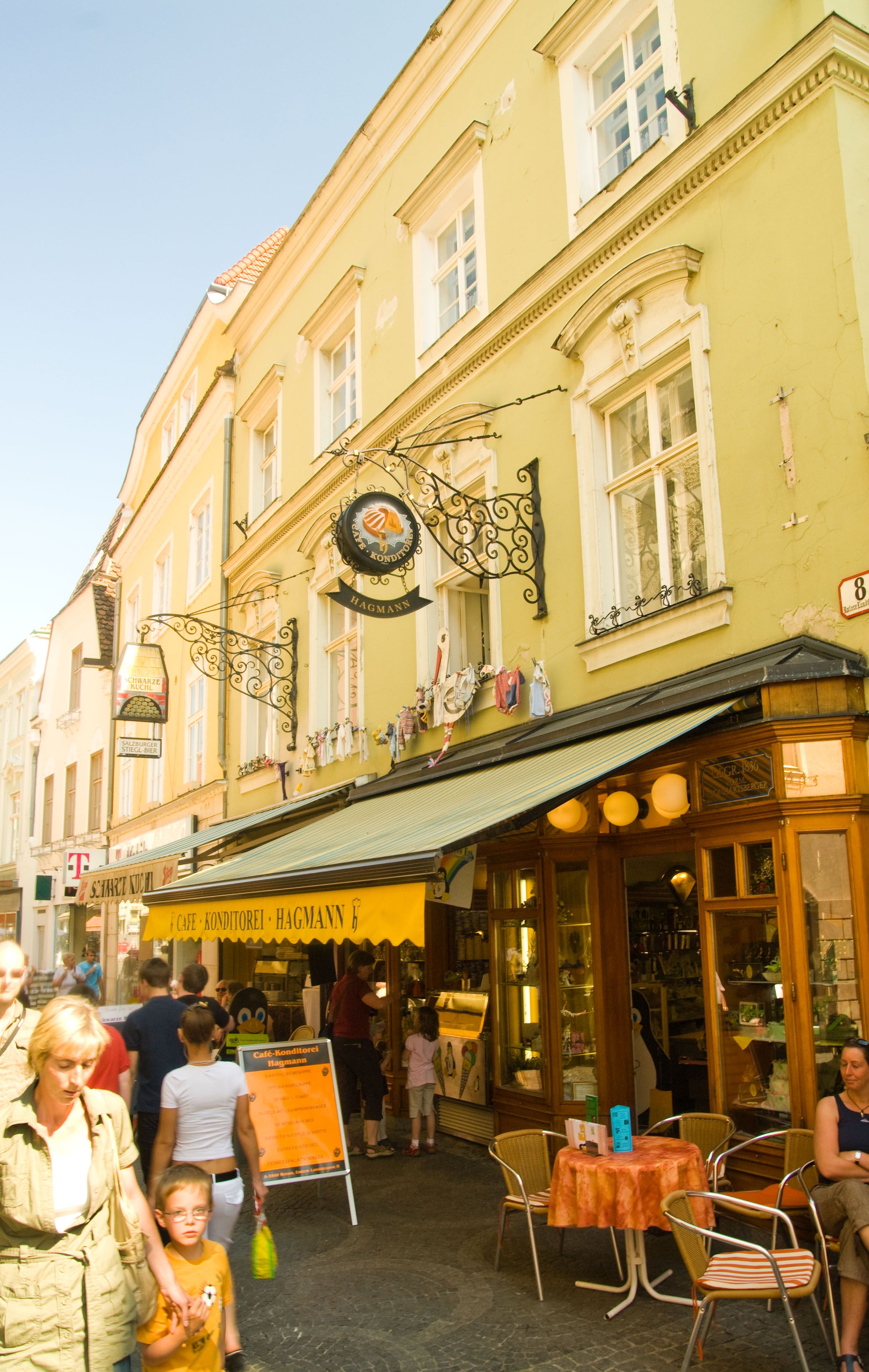 Außenansicht der Konditorei Hagmann mit gelbem Vordach und Straßencafé.