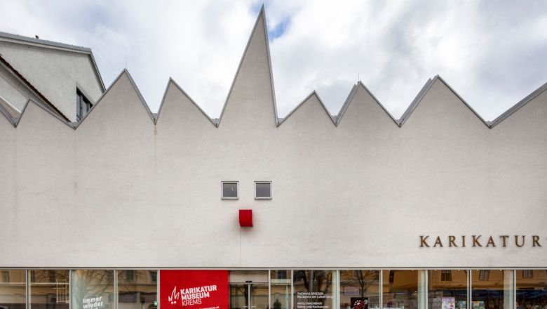 Fassade des Karikaturmuseums Krems mit gezacktem Dach und rotem Quadrat.