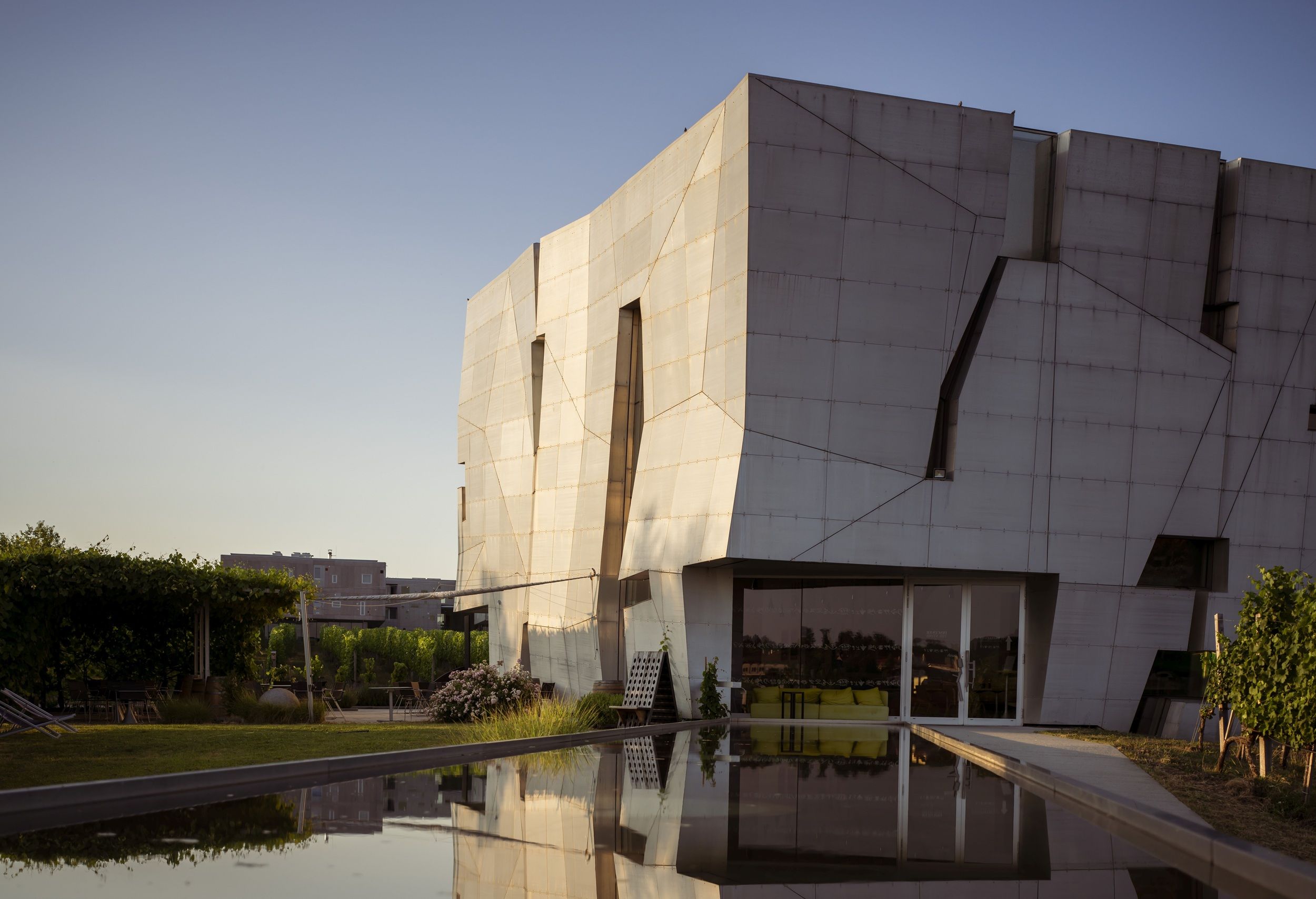 Moderne Architektur eines Gebäudes mit reflektierendem Wasser im Vordergrund.