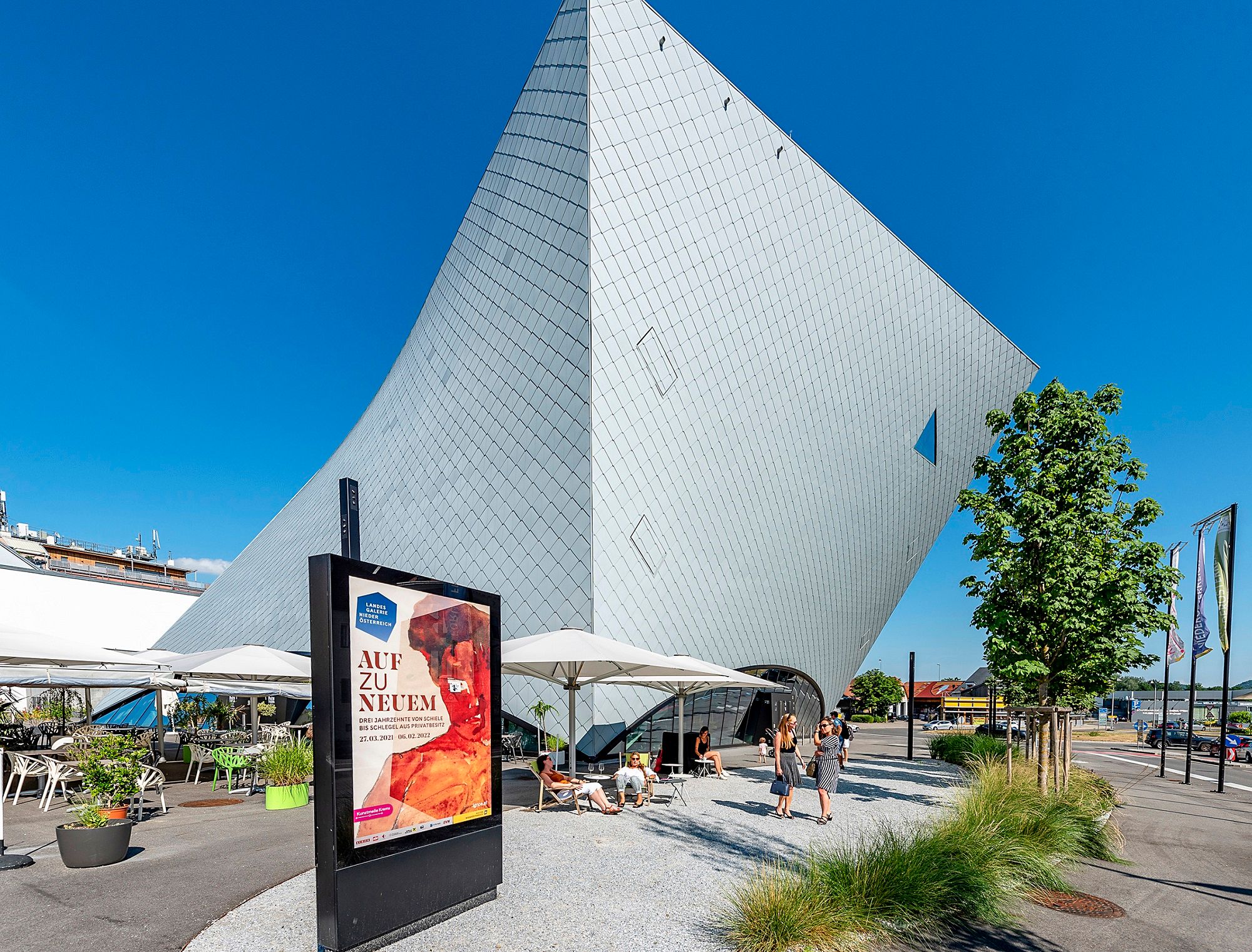 Moderne Architektur der Landesgalerie Niederösterreich in Krems mit Besuchern und Werbeplakat im Vordergrund.