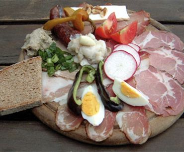 Ein traditionelles Brett mit verschiedenen Wurst- und Käsesorten, Brot, Eiern und Gemüse.