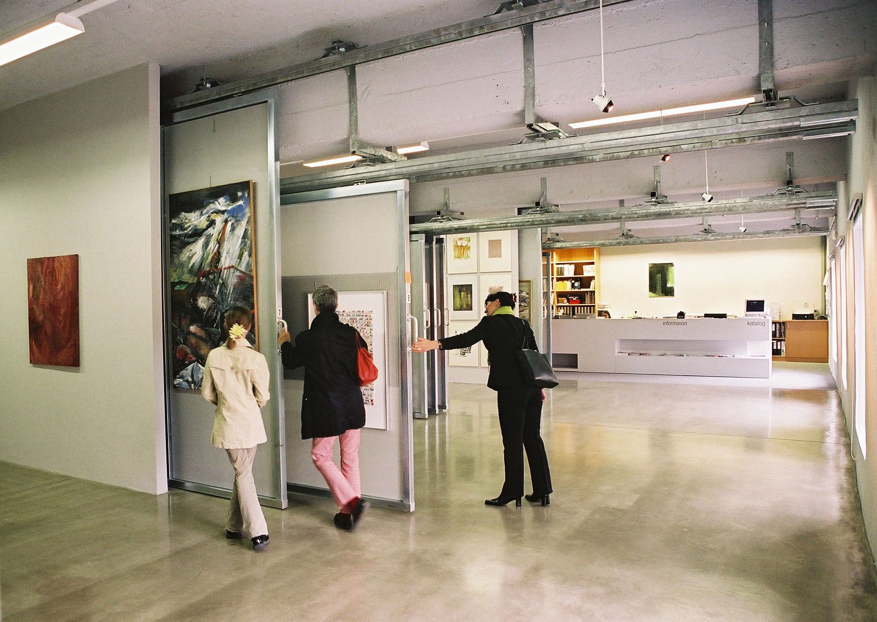 Innenansicht einer Artothek mit Personen, die Kunstwerke betrachten.