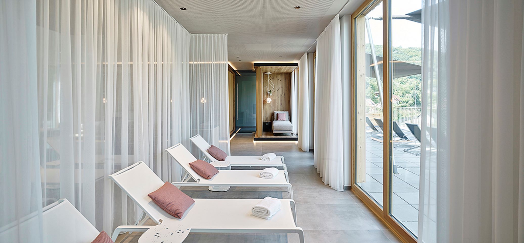 Moderner Spa-Bereich mit Liegestühlen und großen Fenstern.