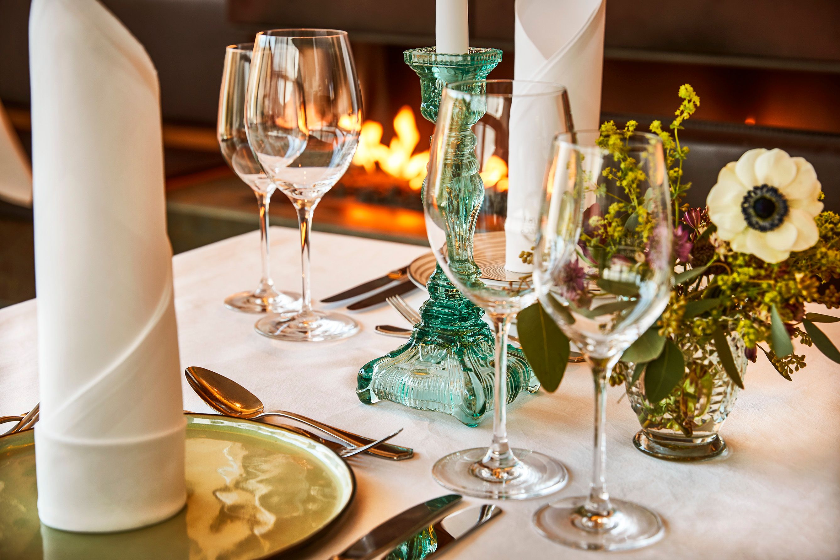 Elegante Tischdekoration mit Gläsern, Kerzenhalter und Blumen im Steigenberger Krems Restaurant.