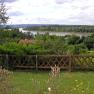 Landscape with river, trees and wooden fence in the foreground.