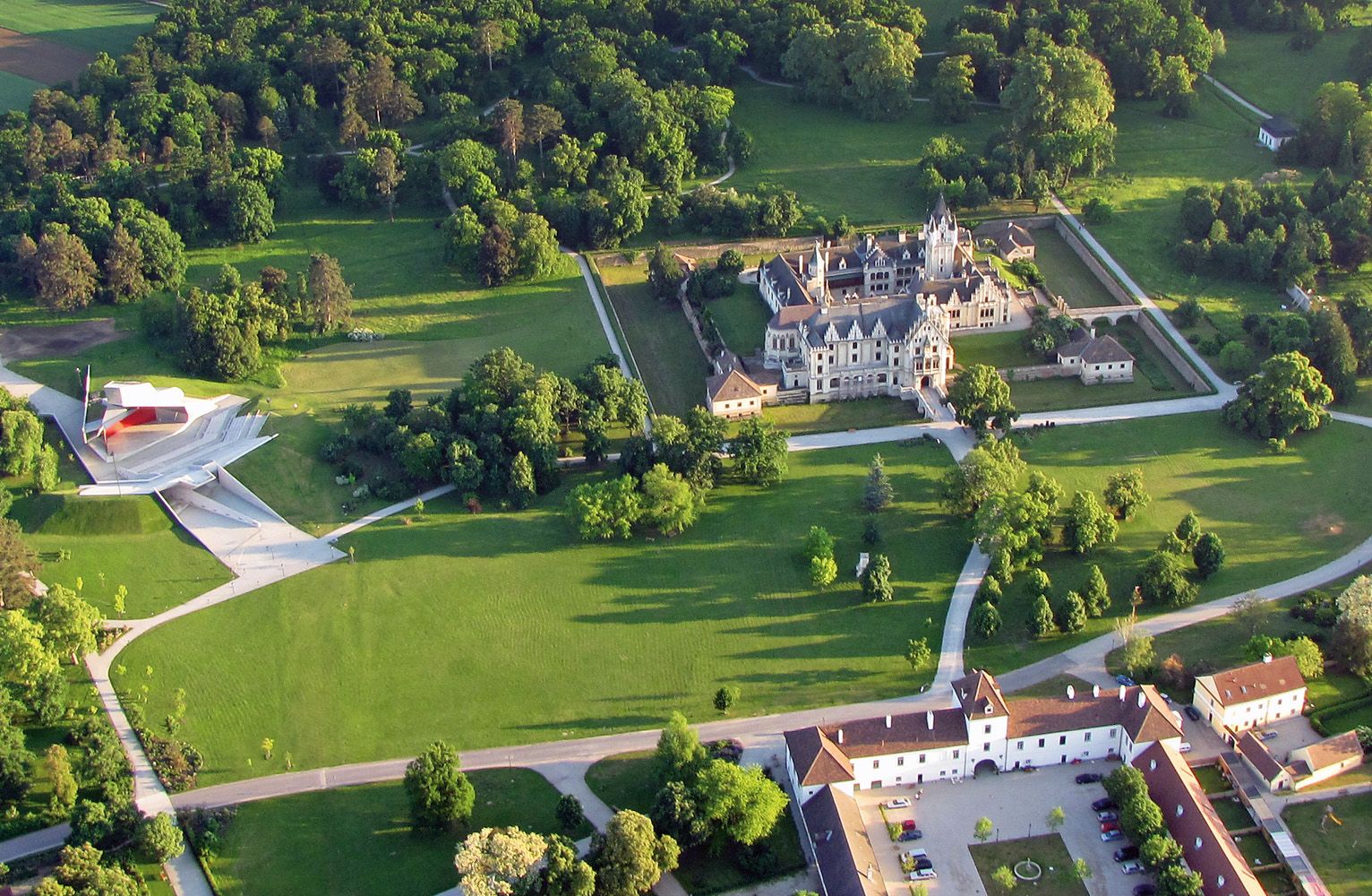 Luftaufnahme von Schloss Grafenegg mit umliegendem Park und moderner Bühne.